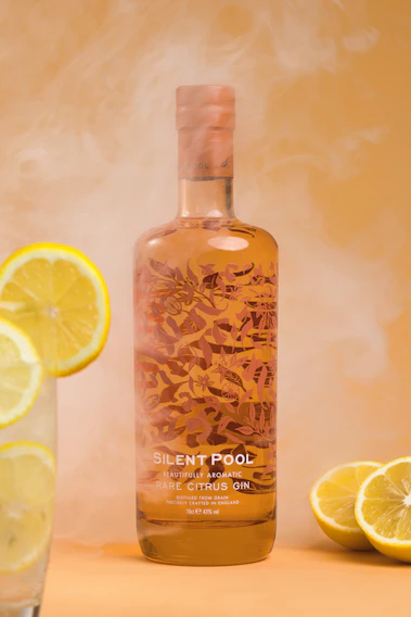 A close-up of a crystal-clear Edinburgh Gin bottle illuminated softly against a deep navy background, highlighting the intricate label details.