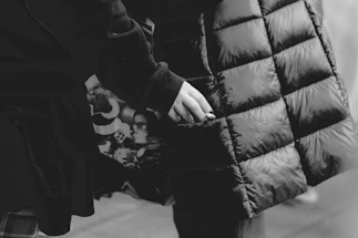 Close-up of a man’s hand resting on a sleek black leather jacket under moody lighting.