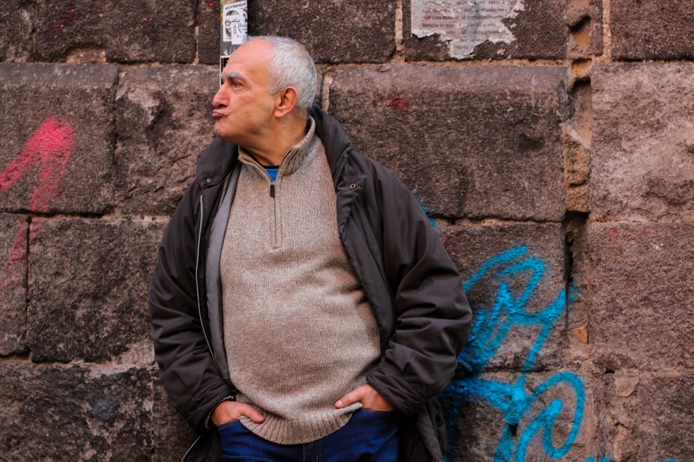 a man standing next to a wall with graffiti on it