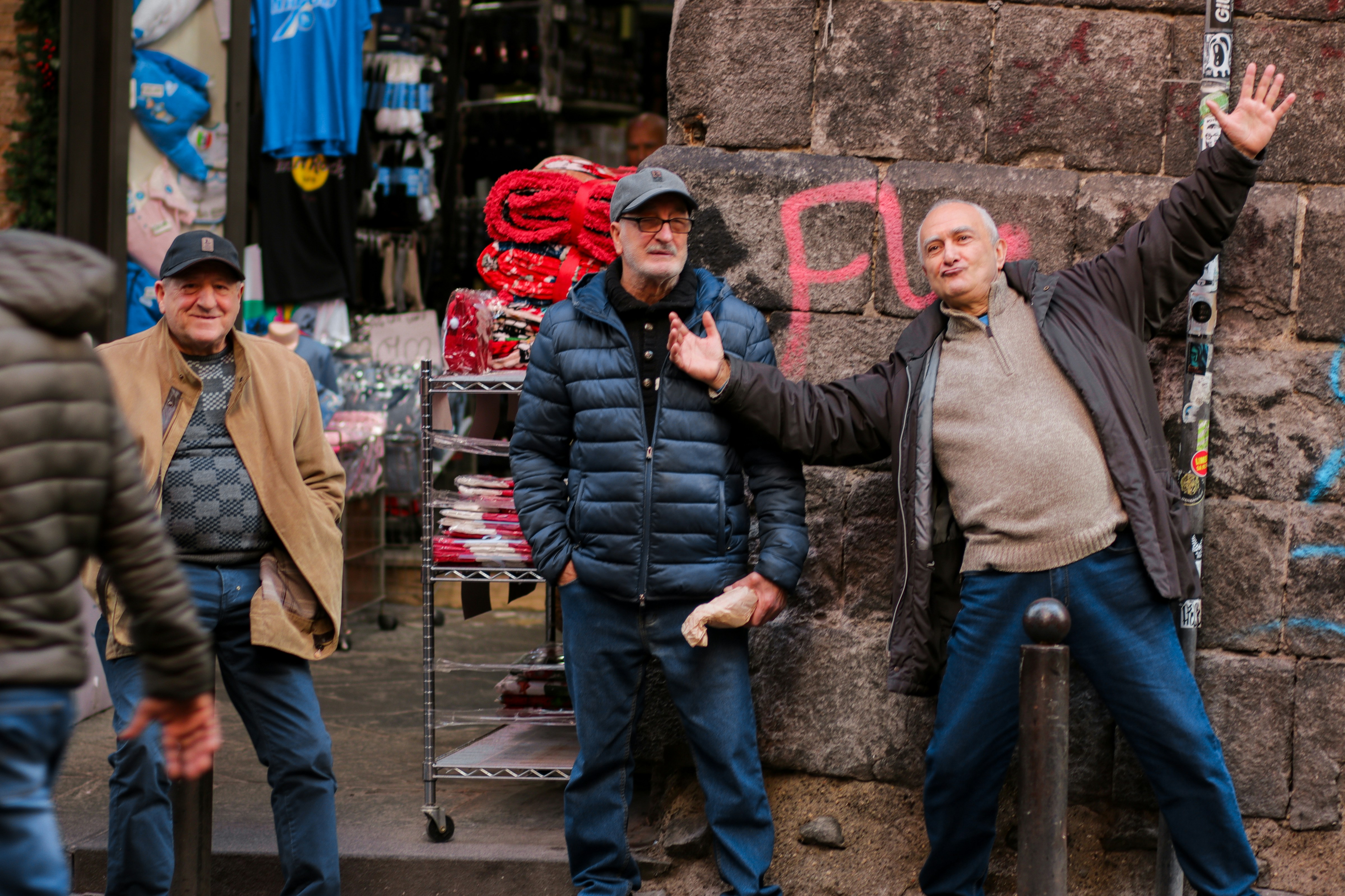 eine Gruppe von Männern, die neben einer Steinmauer stehen