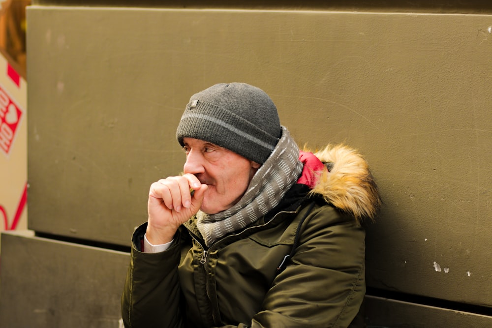 a man sitting on a bench wearing a hat and scarf