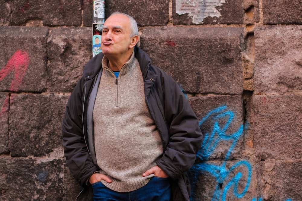 a man standing in front of a brick wall