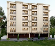 A multi-story residential building with beige walls and multiple balconies. Each floor has large windows with golden brown curtains. There are symmetrical columns enhancing the building’s facade. The foreground includes a manicured lawn and several small trees and shrubs lining the building's base.