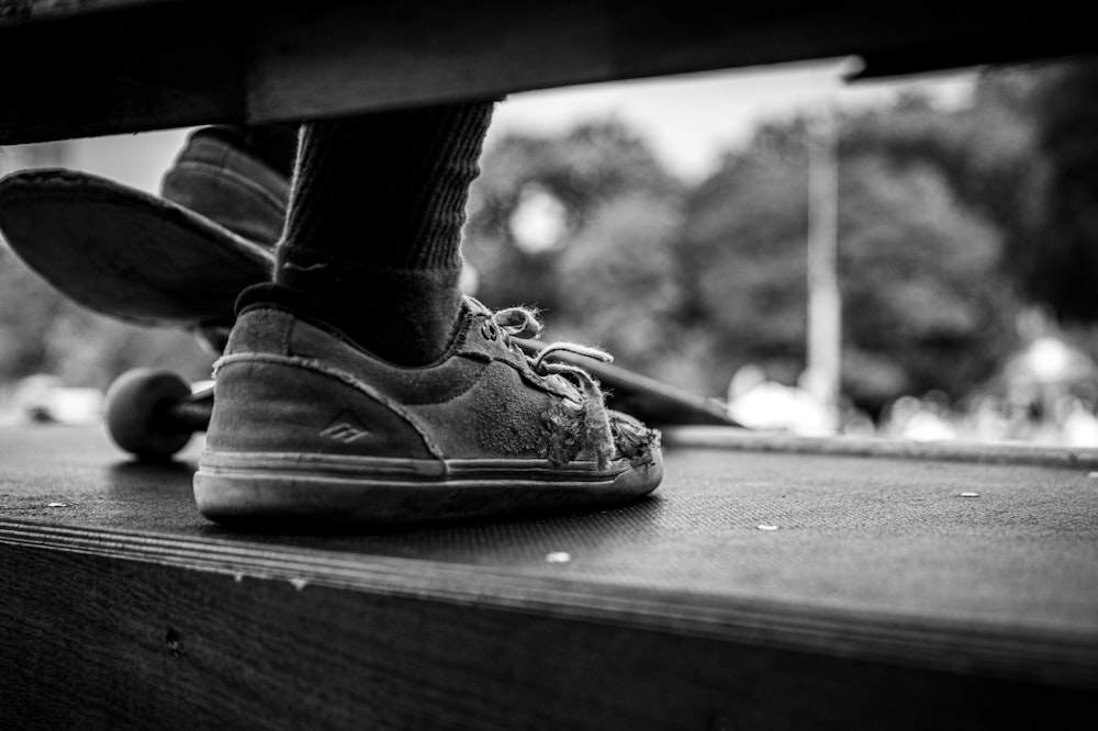 a black and white photo of a person's feet on a bench
