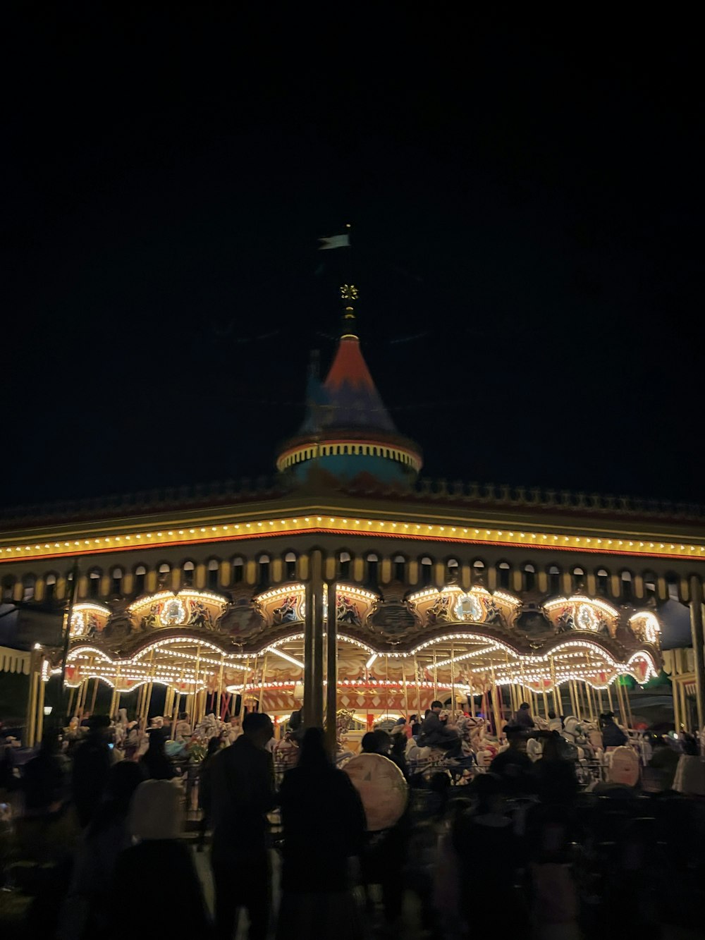 a merry go round at night with people walking around