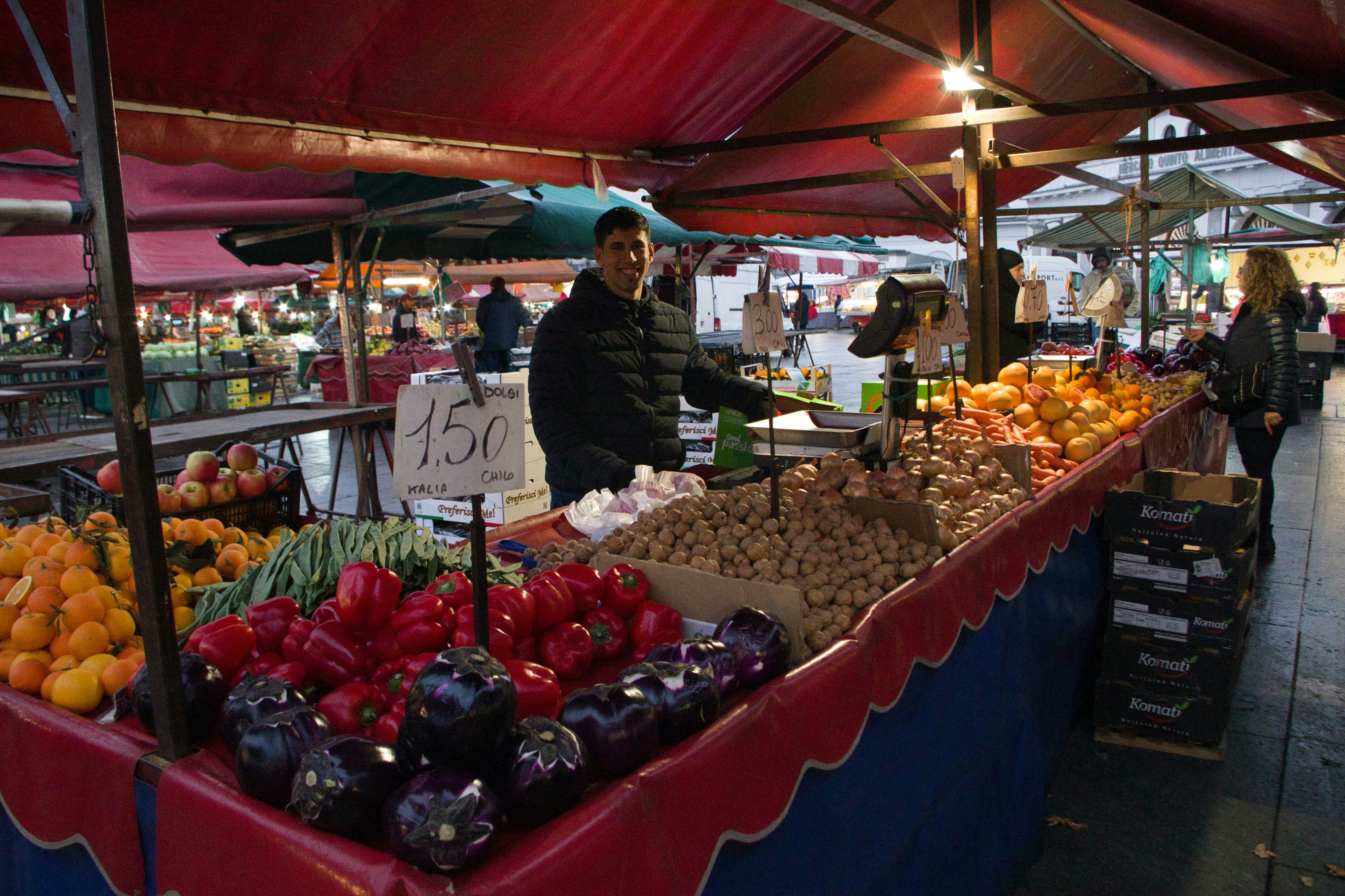 Latino man smiling in outdoor market surrounded by colorful peppers and spices