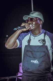 Close-up of Bossman Hogg holding a microphone, fully immersed in his music during an outdoor event.