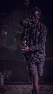 An influencer capturing content with a high-end camera, dressed in black and gold accents.