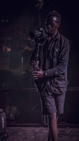 An influencer capturing content with a high-end camera, dressed in black and gold accents.