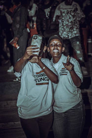 A group photo of friends wearing matching custom t-shirts with unique graphic designs at a local event.