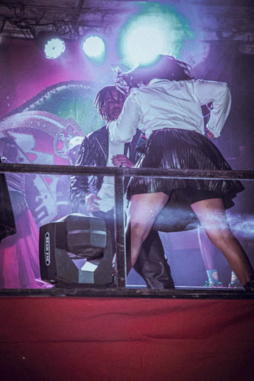 The duo performing energetically on stage with colorful lights in the background.