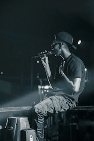 Jottade in casual streetwear, holding a microphone, with a city skyline behind