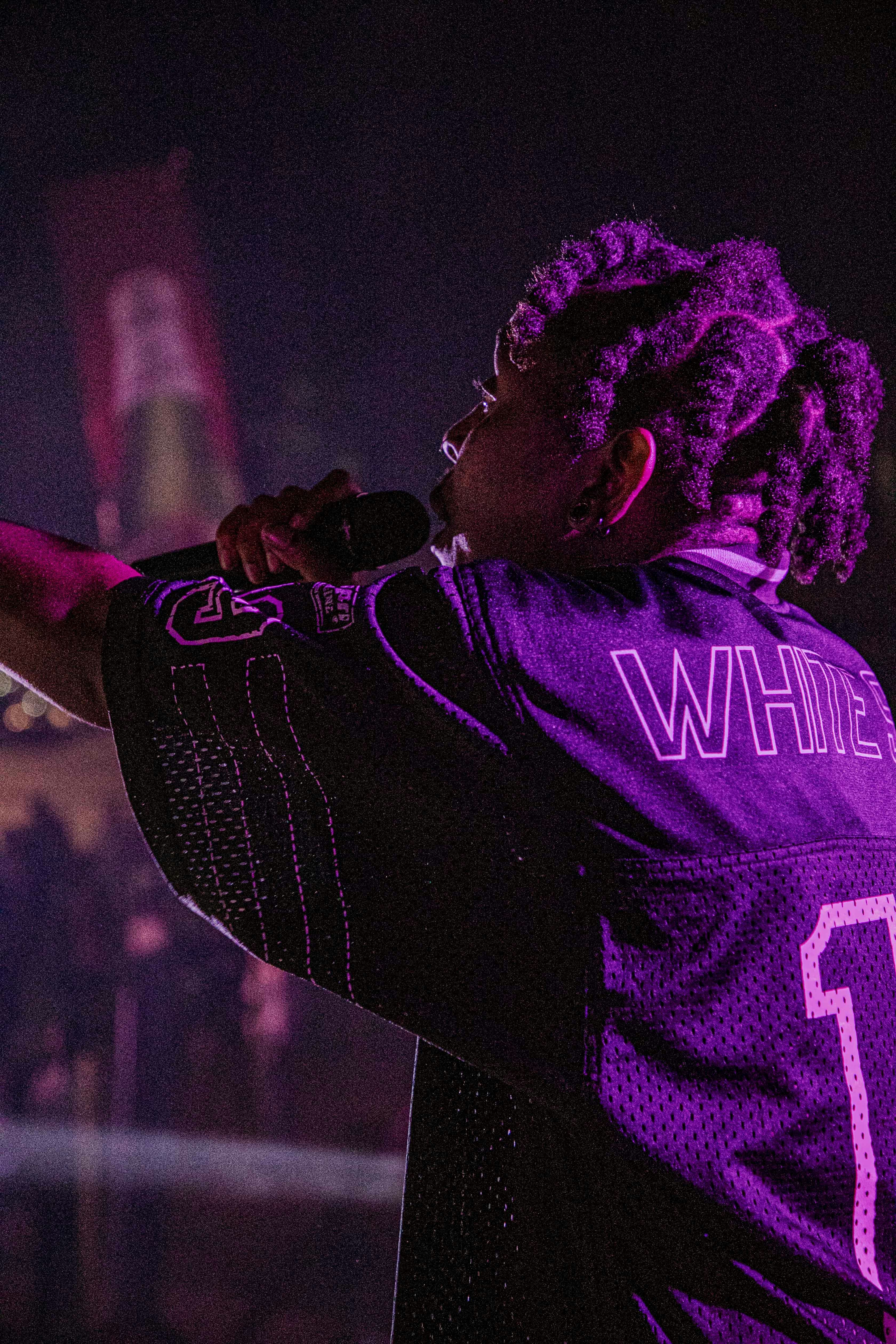 a woman in a purple jersey singing into a microphone