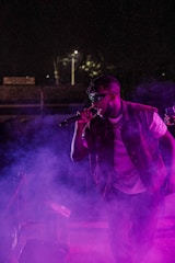 Energetic reggaetón artist performing on stage with purple lights.