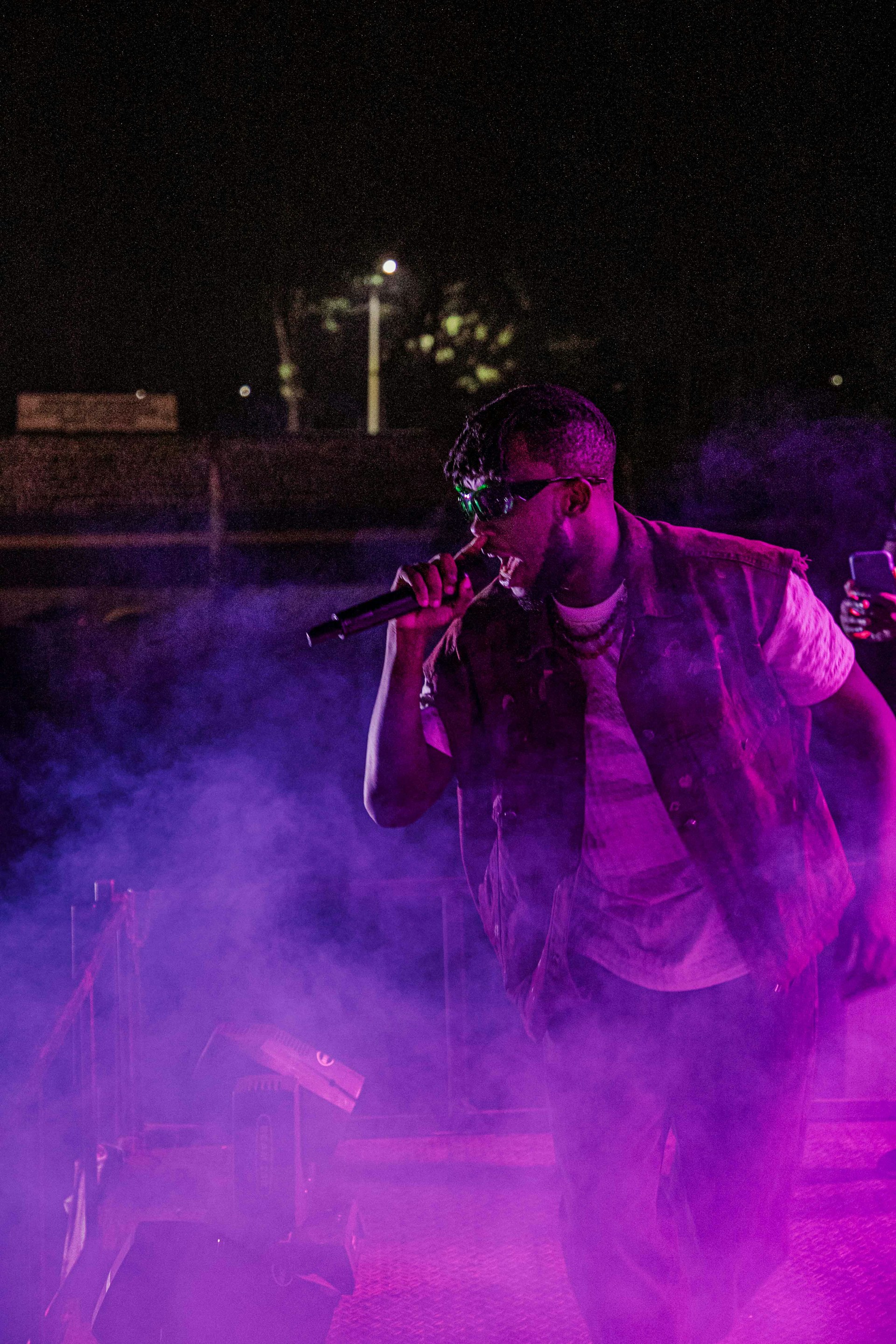 Versavibe performing passionately on stage with a microphone, bathed in soft blue and purple lights.