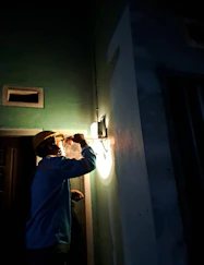 Inspector examining a building with a flashlight, checking for pest signs.
