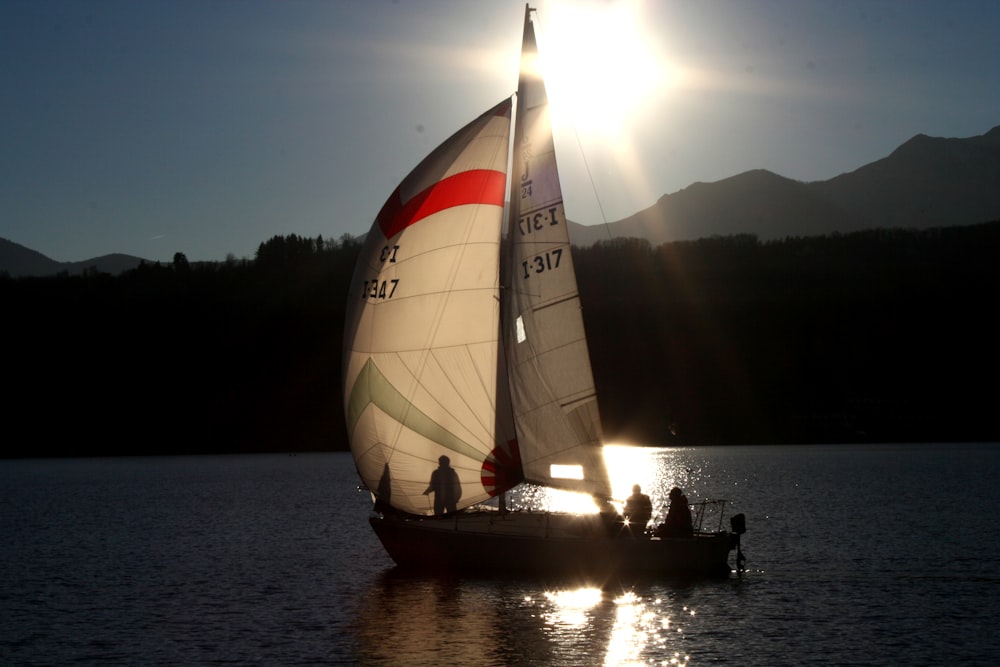 a sailboat with three people on it in the water