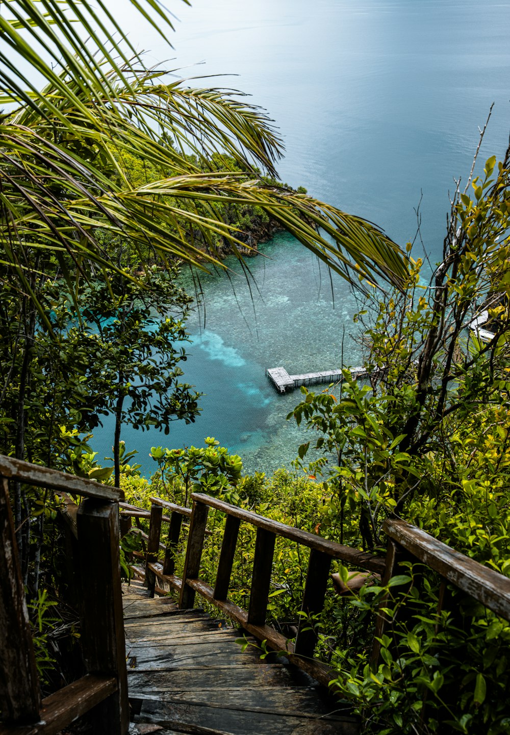 a wooden staircase leading to a beach with a boat in the water