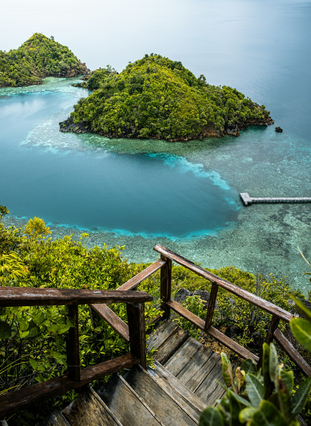 a wooden staircase leading to an island in the middle of the ocean