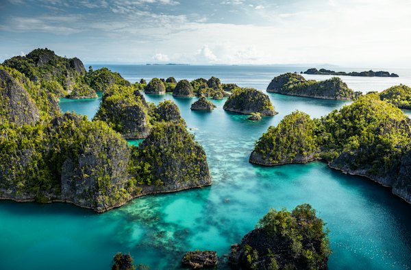 An aerial view of a body of water surrounded by rocks — Raja Ampat, Indonesia