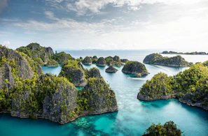 A panoramic view of lush green islands scattered across bright blue waters from the deck of a boat