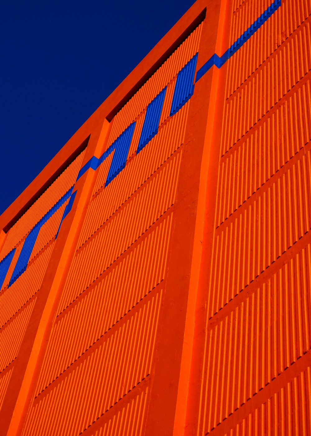 a tall orange building with a blue sky in the background