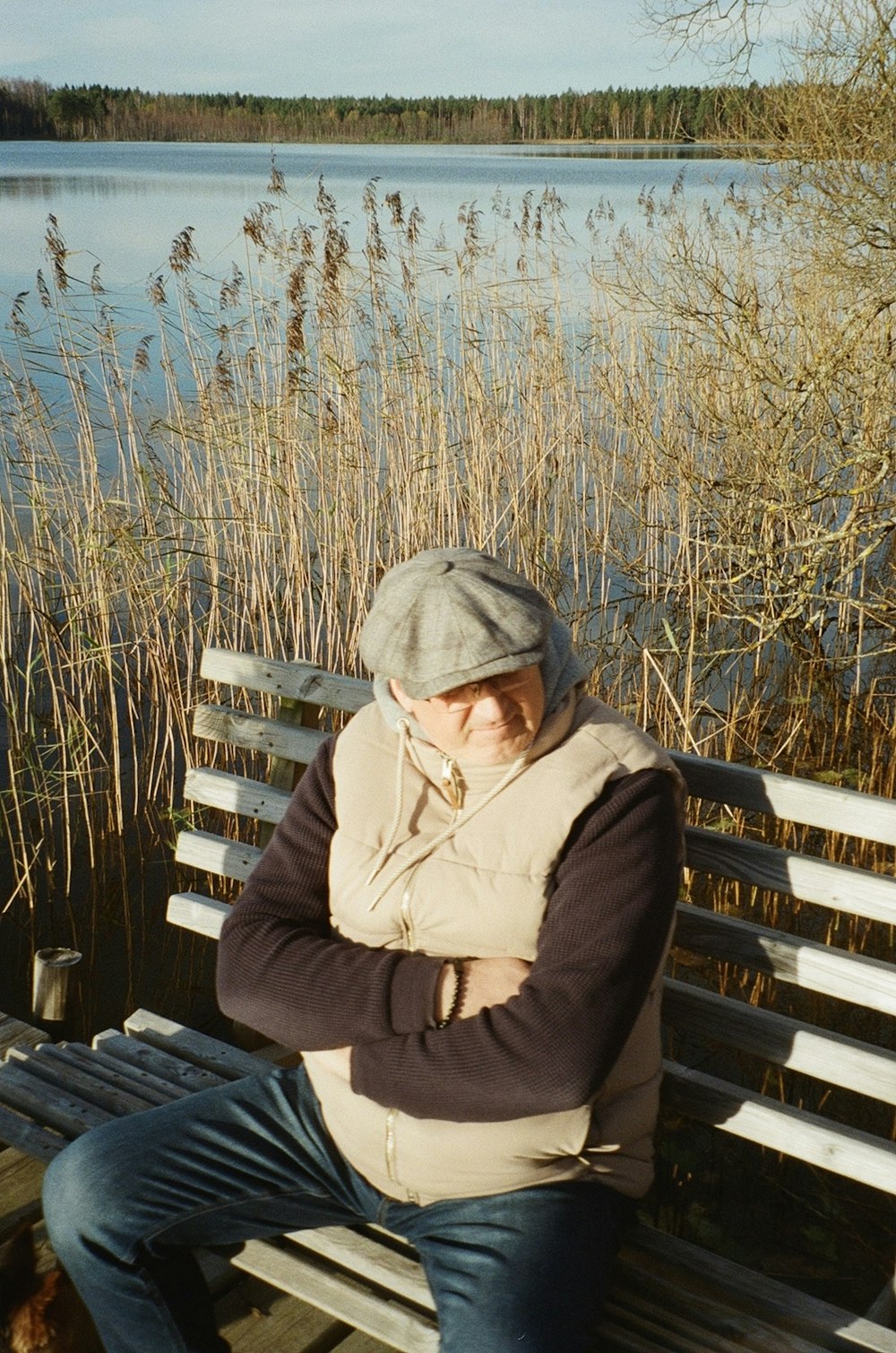 Un hombre sentado en un banco junto a un cuerpo de agua