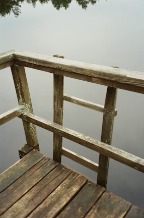 A wooden deck with water droplets shimmering under soft light blue hues after a detailed pressure wash.