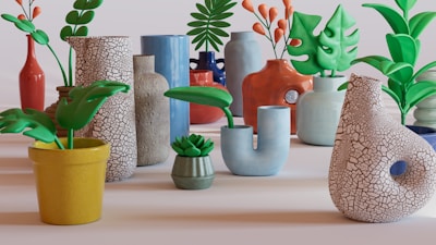 An arrangement of various ceramic vases and planters, each with distinct shapes and textures. Some feature leafy plants and succulents, adding a natural element to the display. The vases exhibit a mix of colors like orange, blue, and white with different patterns, such as cracked and smooth surfaces.