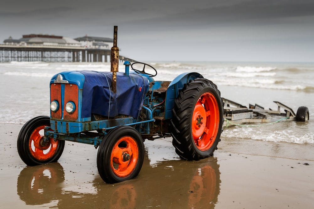 a blue tractor parked on top of a sandy beach