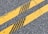 Two parallel yellow lines on an asphalt road with cracks and leaves scattered on the surface.