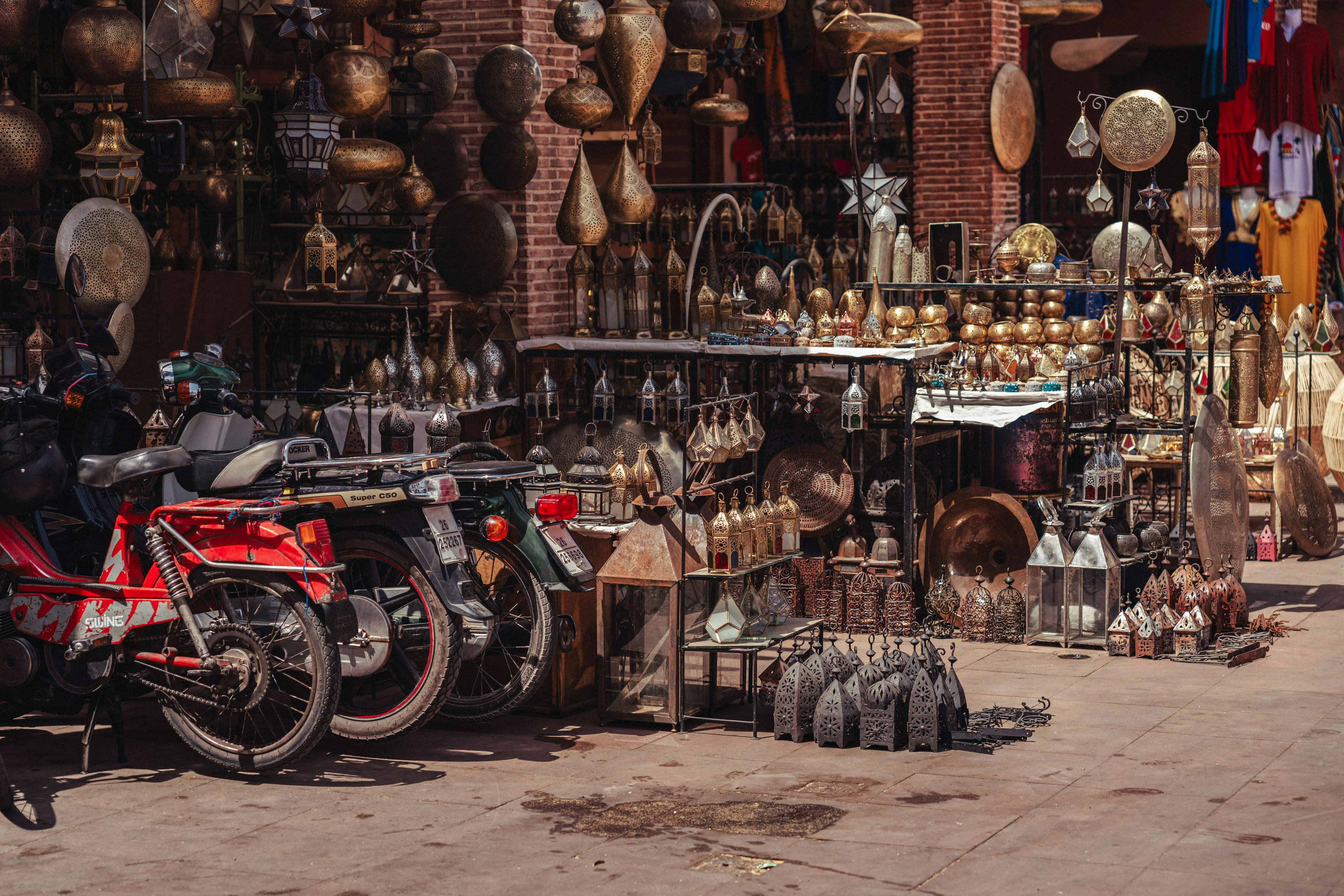 A red motorcycle parked in front of a store filled with pots and pans