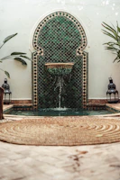 A vibrant Moroccan mosaic fountain surrounded by lush greenery in the riad garden.