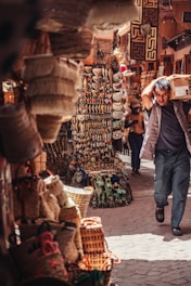 A bustling marketplace filled with an array of vibrant items. Multiple woven baskets are displayed on the left, while in the center, a variety of hanging artifacts, heart-shaped decorations, and small trinkets are visible.