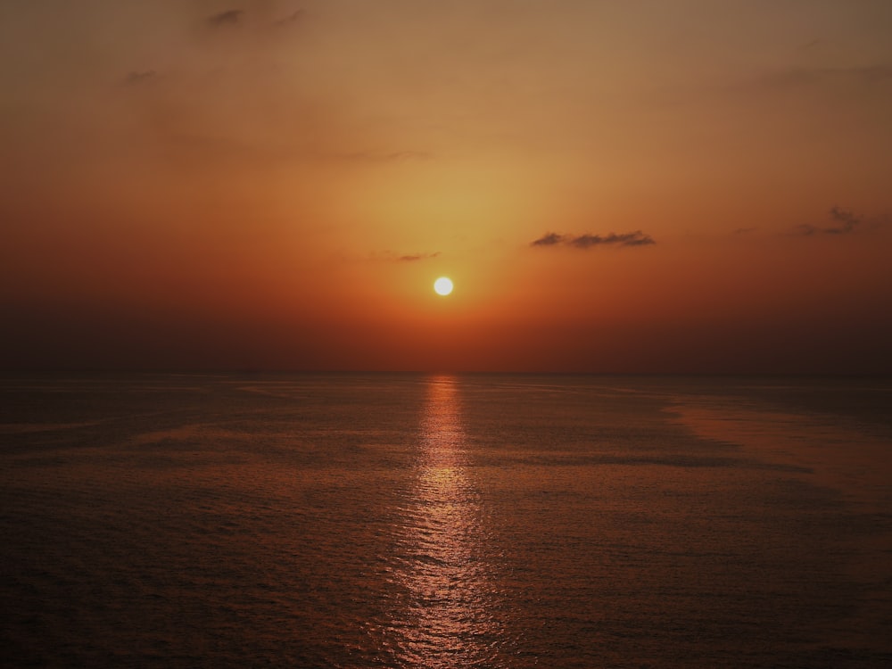 the sun is setting over the ocean on a cloudy day