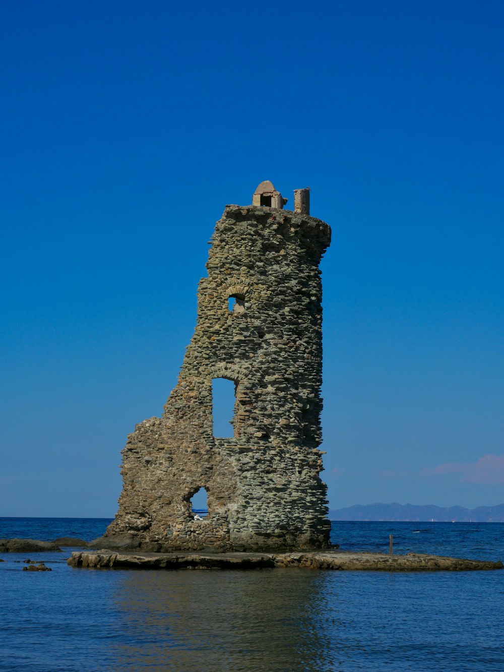 a stone tower sitting in the middle of a body of water