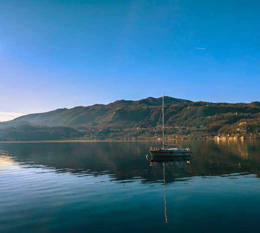 A serene lake scene with a Nauticavibe charter boat gently floating under a clear blue sky.