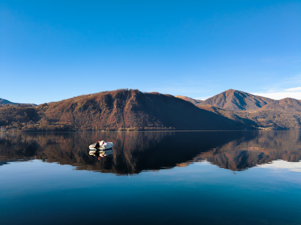 a person sitting on a rock in the middle of a lake