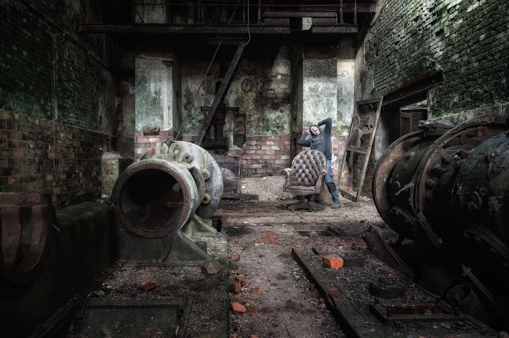 a man standing in an old factory with a large pipe