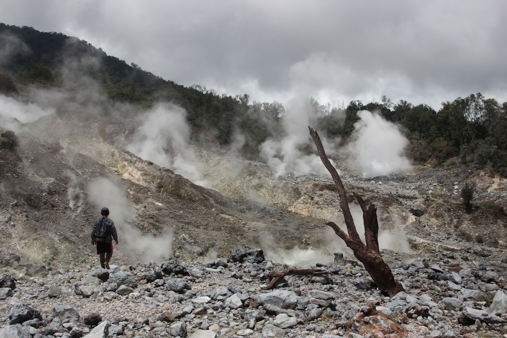 a man standing in a rocky area with steam coming out of the ground