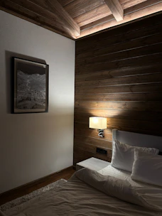 A cozy bedroom accent wall decorated with elegant 3D PVC panels in warm tones.