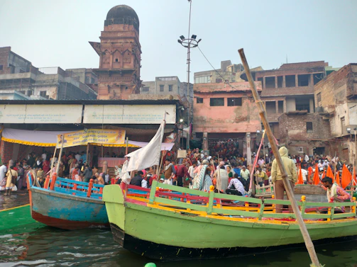 A colorful boat docked at the bustling riverbank of Dhaka, framed by lively street scenes.