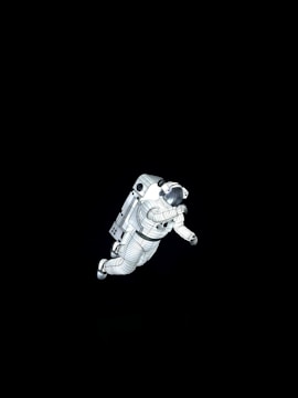 An astronaut in a spacesuit floats in a dark space environment, with clear details of the suit design and equipment.