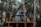 Finished A-frame cabin with wooden deck and warm interior lights nestled in forested hills