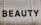 Large, bold letters spelling the word 'BEAUTY' are displayed on a textured surface. The background appears to have a subtle beige tint with visible creases or folds.