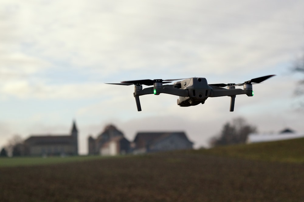 a small airplane flying over a field with houses in the background