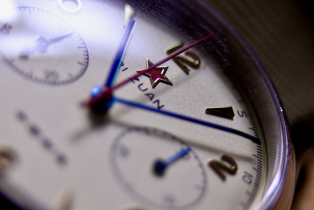 a close up of a white watch with blue hands