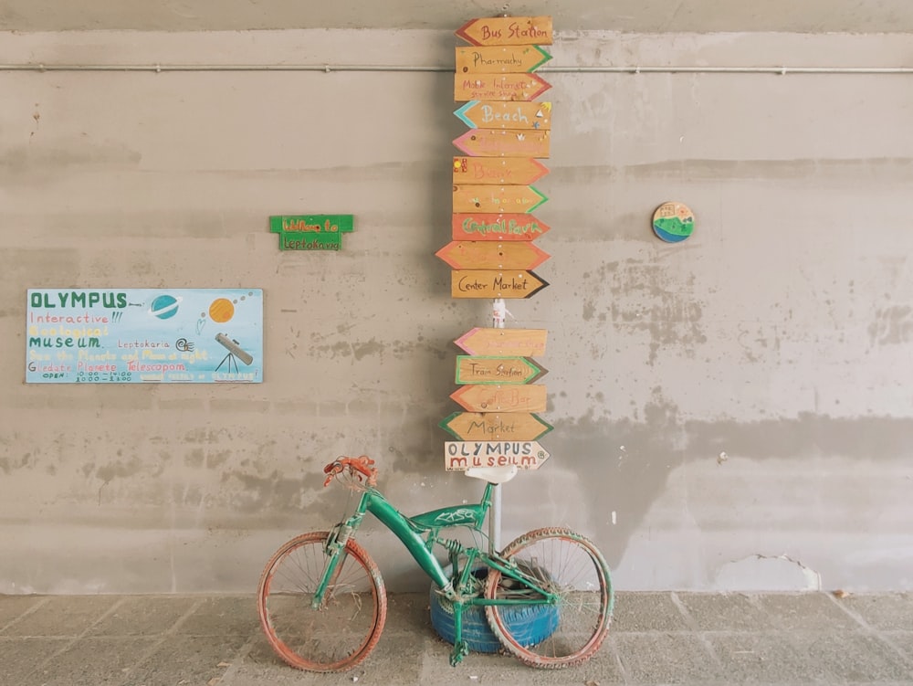 a bicycle parked next to a sign on a wall