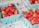 Several cartons of fresh strawberries are neatly arranged in teal-colored baskets, sitting on a textured surface. The strawberries are bright red with green stems, and they appear freshly picked.