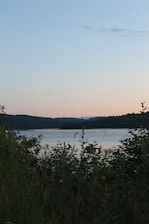 A serene view of Mayfair Lake Resort surrounded by lush greenery and calm waters at sunset.
